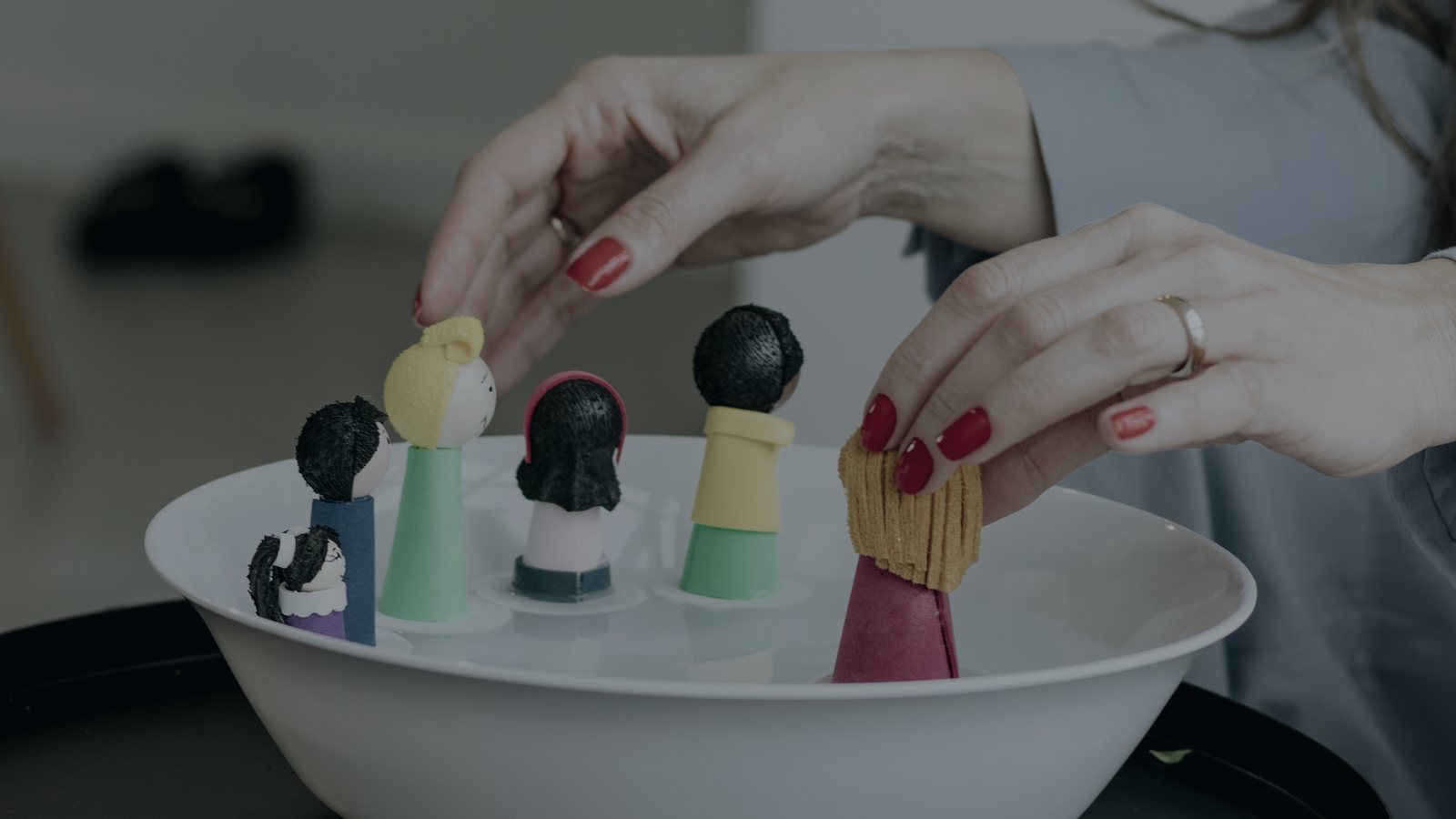 Mãos posicionando bonecos numa bacia com água
